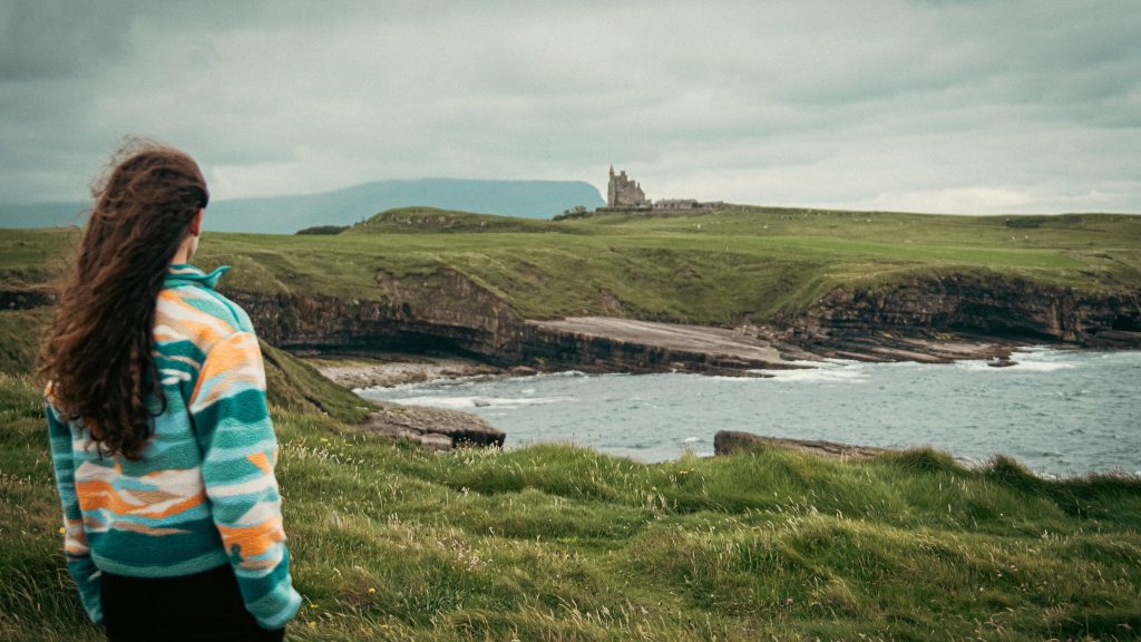 A woman looks out over an ocean bay at Classiebawn Castle in Ireland