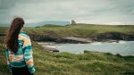 A woman looks out over an ocean bay at Classiebawn Castle in Ireland